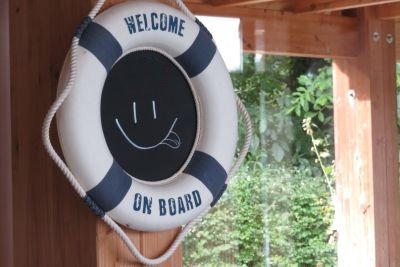 Rettungsring hängt an Kreidetafel mit Smiley, am Ring ist der Text Welcome on board zu lesen