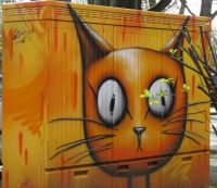 Foto eines Stromkastens, der mit einem orange-farbenen Katzenkopf bemalt ist